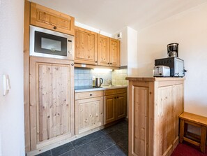 Una cocina con armarios de madera, microondas, cafetera y tostadora.