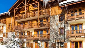 A multi-story wooden chalet with balconies, surrounded by snow. - Cozy apartment with balcony - 4 guests (La Toussuire)