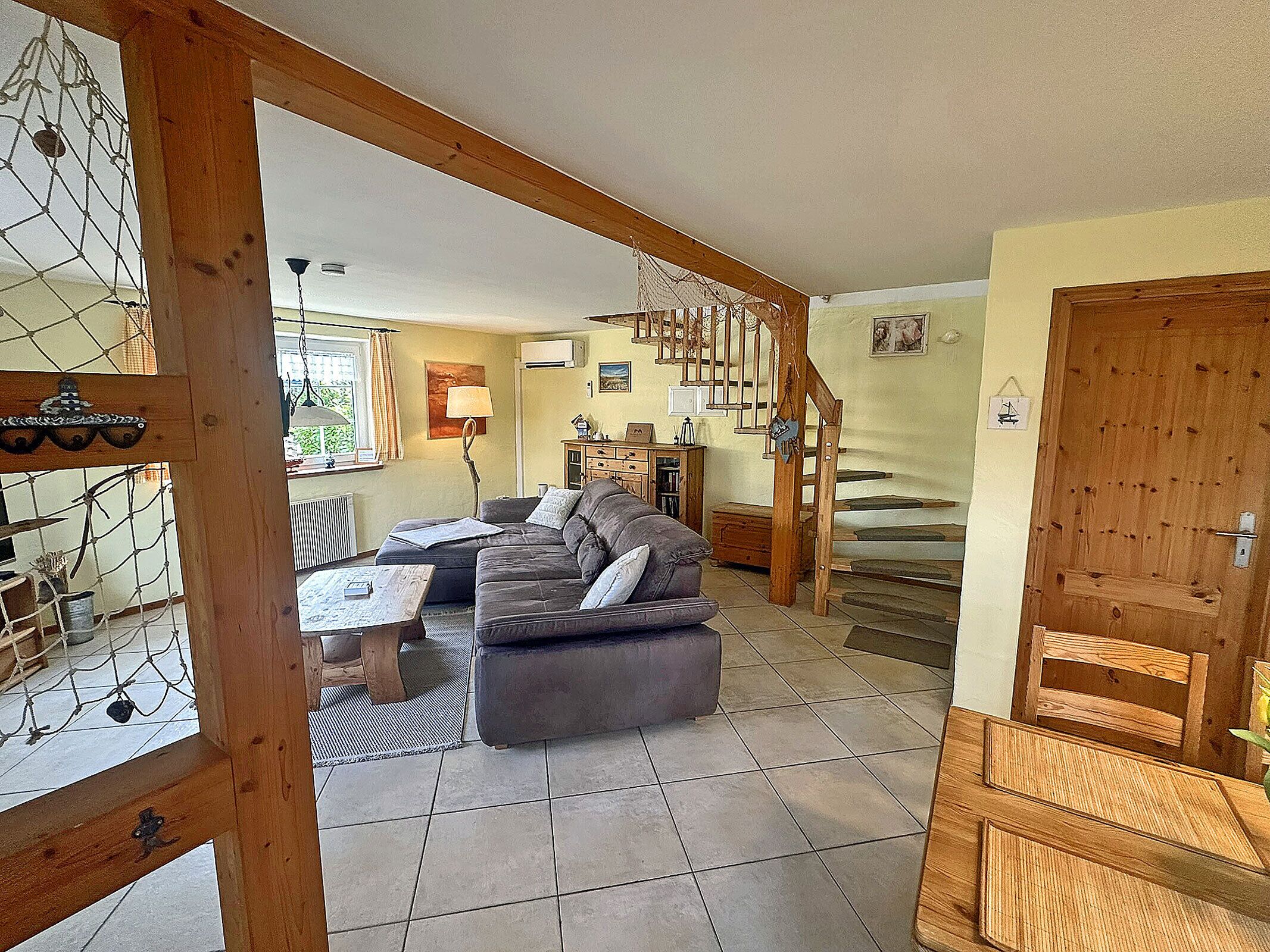 A spacious living area with a sofa, a coffee table, and a staircase leading to an upper floor.