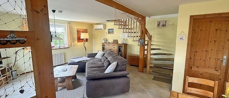 Un vaste espace de vie comprenant un canapé, une table basse et un escalier menant à l’étage supérieur.