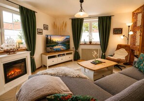 Ein gemütliches Wohnzimmer mit Kamin, Fernseher und einer komfortablen Sitzecke.