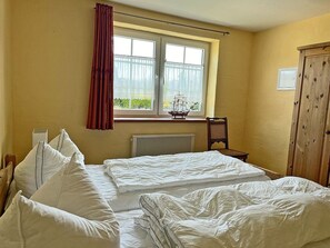 A room with two beds, a window with curtains, a radiator, a wooden cabinet, and a chair. - 900 meters to the beach, 2 bedrooms, sleeps up to 4, Wi-Fi, pets allowed by arrangement (Breege)