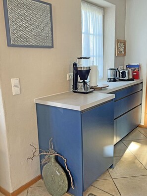 Una cocina con cafetera, tostadora y hervidor en la encimera.