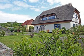 A traditional building with a sloped roof, a thatched roof extension, and a well-maintained garden with various plants. - 900 meters to the beach, 2 bedrooms, sleeps up to 4, Wi-Fi, pets allowed by arrangement (Breege)