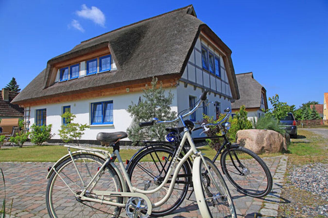 A traditional house with a thatched roof, a bicycle parked in front, and a clear blue sky.