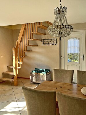 A wooden staircase leading to a second floor, a chandelier, a dining table with chairs, and a door with a window. - 900 meters to the beach, 2 bedrooms, sleeps up to 4, Wi-Fi, pets allowed by arrangement (Breege)