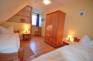 A bedroom with two beds, a wooden wardrobe, a chair, and a small table with lamps. - 900 meters to the beach, 2 bedrooms, sleeps up to 4, Wi-Fi, pets allowed by arrangement (Breege)