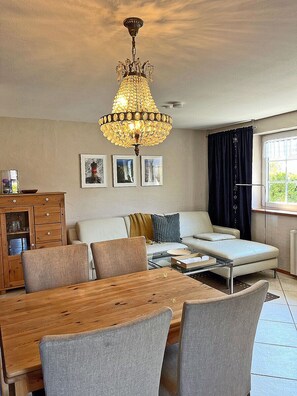 A living room with a chandelier, sofa, dining table, and chairs. - 900 meters to the beach, 2 bedrooms, sleeps up to 4, Wi-Fi, pets allowed by arrangement (Breege)