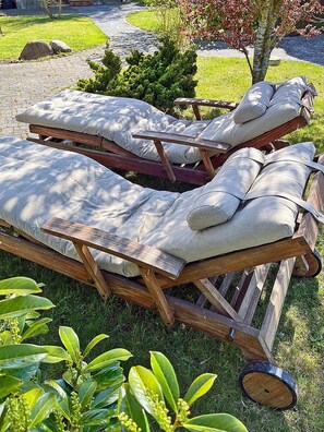 A set of wooden lounge chairs with cushions, positioned on a grassy area with a stone pathway and greenery in the background. - 900 meters to the beach, 2 bedrooms, sleeps up to 4, Wi-Fi, pets allowed by arrangement (Breege)