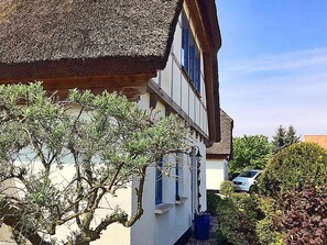 A two-story building with a thatched roof, a balcony, and a car parked in the background. - 900 meters to the beach, 2 bedrooms, sleeps up to 4, Wi-Fi, pets allowed by arrangement (Breege)