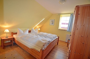 A bedroom with a wooden bed, a nightstand, a lamp, a radiator, and a window with curtains. - 900 meters to the beach, 3 bedrooms, sleeps up to 6, Wi-Fi, pets allowed by arrangement (Breege)