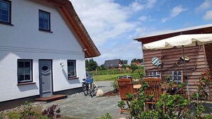 A white building with a thatched roof, a wooden structure with a white awning, and outdoor seating. - 900 meters to the beach, 2 bedrooms, sleeps up to 4, Wi-Fi, pets allowed by arrangement (Breege)