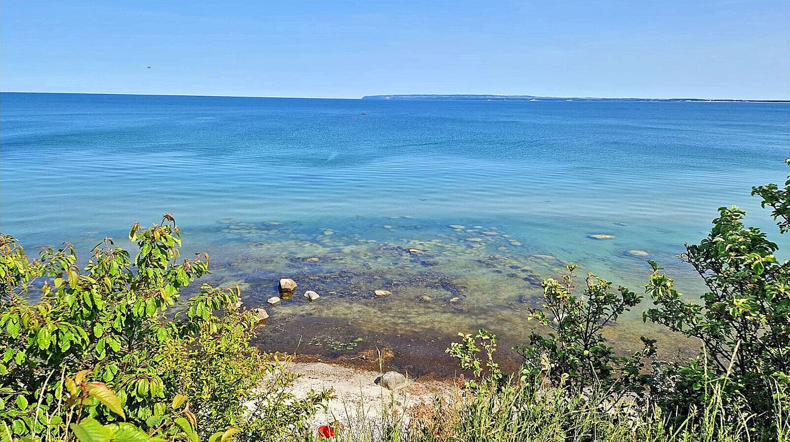 Un paysage côtier caractérisé par une eau claire, des rochers et une végétation luxuriante.