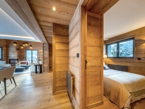 A wooden cabin interior with a bed, a dining area, and a view of the outdoors. - Bright apartment - 10 guests (Megève)