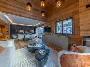A modern log cabin interior with a dining area, kitchen, and living space. - Bright apartment - 10 guests (Megève)