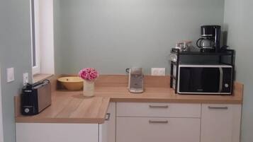 Eine Küchenzeile mit Mikrowelle, Kaffeemaschine und einer Schüssel auf der Arbeitsfläche.