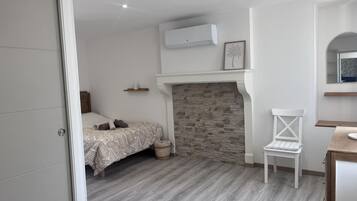 Ein Schlafzimmer mit Bett, einem Sessel, einem Kamin und einem Spiegel.