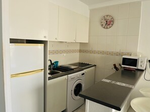 A compact kitchen with a washing machine, a microwave, and a sink. - Charming apartment near the sea - 4 guests (Denia)