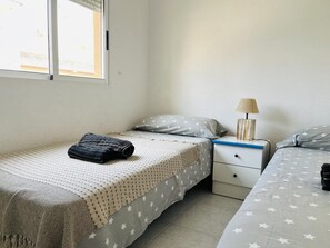 Un dormitorio con dos camas, una mesita de noche y una lámpara.
