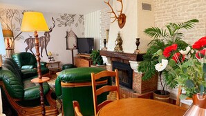 Ein gemütliches Wohnzimmer mit einem grünen Ledersofa, einem Holztisch und einem Kamin.