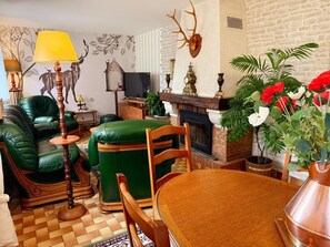 Ein gemütliches Wohnzimmer mit einem grünen Ledersofa, einem Holztisch und einem Kamin.
