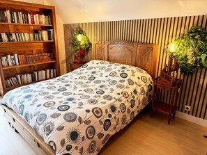 Ein Schlafzimmer mit einem großen Bett, einer Holzbibliothek und einer Wandleuchte.