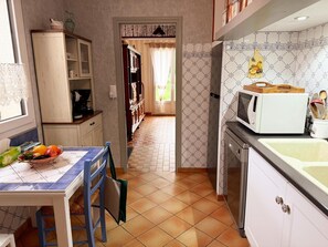 A kitchen with a dining table, chairs, a microwave, and cabinets. - Charming cottage between nature and culture - 6 guests (Thoury)