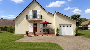 Ein zweistöckiges Haus mit Balkon, einem roten Sonnenschirm und einer Garage.