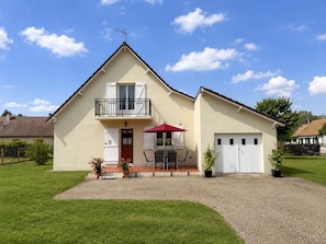 Ein zweistöckiges Haus mit Balkon, einem roten Sonnenschirm und einer Garage.
