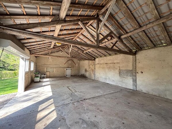 An interior with a concrete floor, wooden beams, and a metal roof.