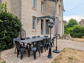 A stone building with a paved patio, outdoor seating, and a lamp post.