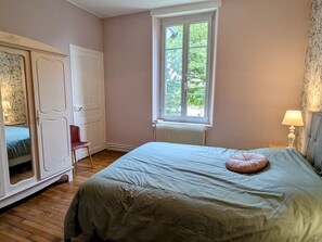 Ein Schlafzimmer mit Bett, Fenster, Heizkörper, Kleiderschrank und Stuhl.