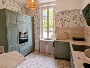 A compact kitchen with a built-in oven, a sink, and a window providing natural light.