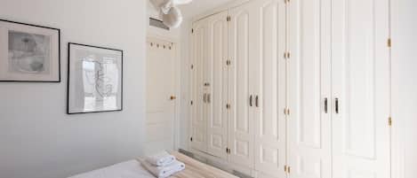 A bedroom with a large bed, a wardrobe, and two framed pictures on the wall.