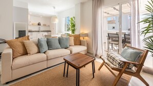 A modern living room with a sofa, a wooden coffee table, and a wicker chair. - Modern penthouse with mountain view - 6 guests (Marbella)