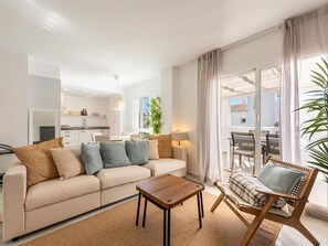 A modern living room with a sofa, a wooden coffee table, and a wicker chair. - Modern penthouse with mountain view - 6 guests (Marbella)