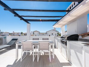 A rooftop patio with a table and chairs, a grill, and a view of the neighborhood. - Modern penthouse with mountain view - 6 guests (Marbella)