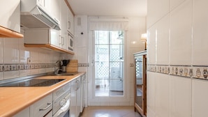 Cocina con gabinetes blancos, encimera de madera y salpicadero de azulejos.