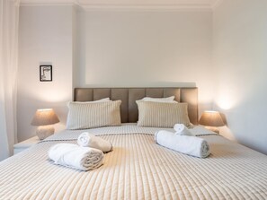 Ein Hotelzimmer mit einem großen Bett, zwei Nachttischlampen und einem gerahmten Bild an der Wand.