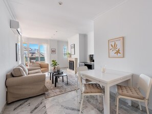 A modern living room with a sofa, a dining table, and a fireplace. - Quiet apartment with terrace - 4 guests (Marbella)
