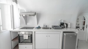 Kompakti keittiö, jossa on sisäänrakennettu uuni, pesuallas ja pienikokoinen jääkaappi.