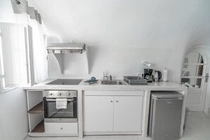 A compact kitchen with a built-in oven, a sink, and a compact refrigerator. - Apartment 'Grand Suite Twin' with Wi-Fi and Air Conditioning (Fira)