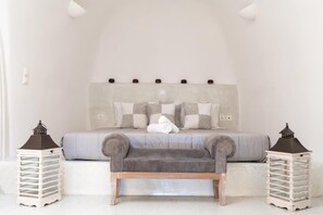 A bedroom with a bed, pillows, a bench, and two lanterns. - Apartment 'Grand Suite Twin' with Wi-Fi and Air Conditioning (Fira)