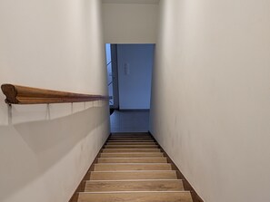 Eine schmale Treppe mit hölzernen Stufen und einem Holzgeländer.