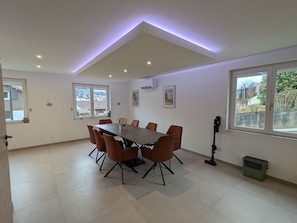A modern dining room with a rectangular table and six chairs, large windows with a view, and a ceiling with recessed lighting. - House with mountain view, near center - 6 guests (Gérardmer)