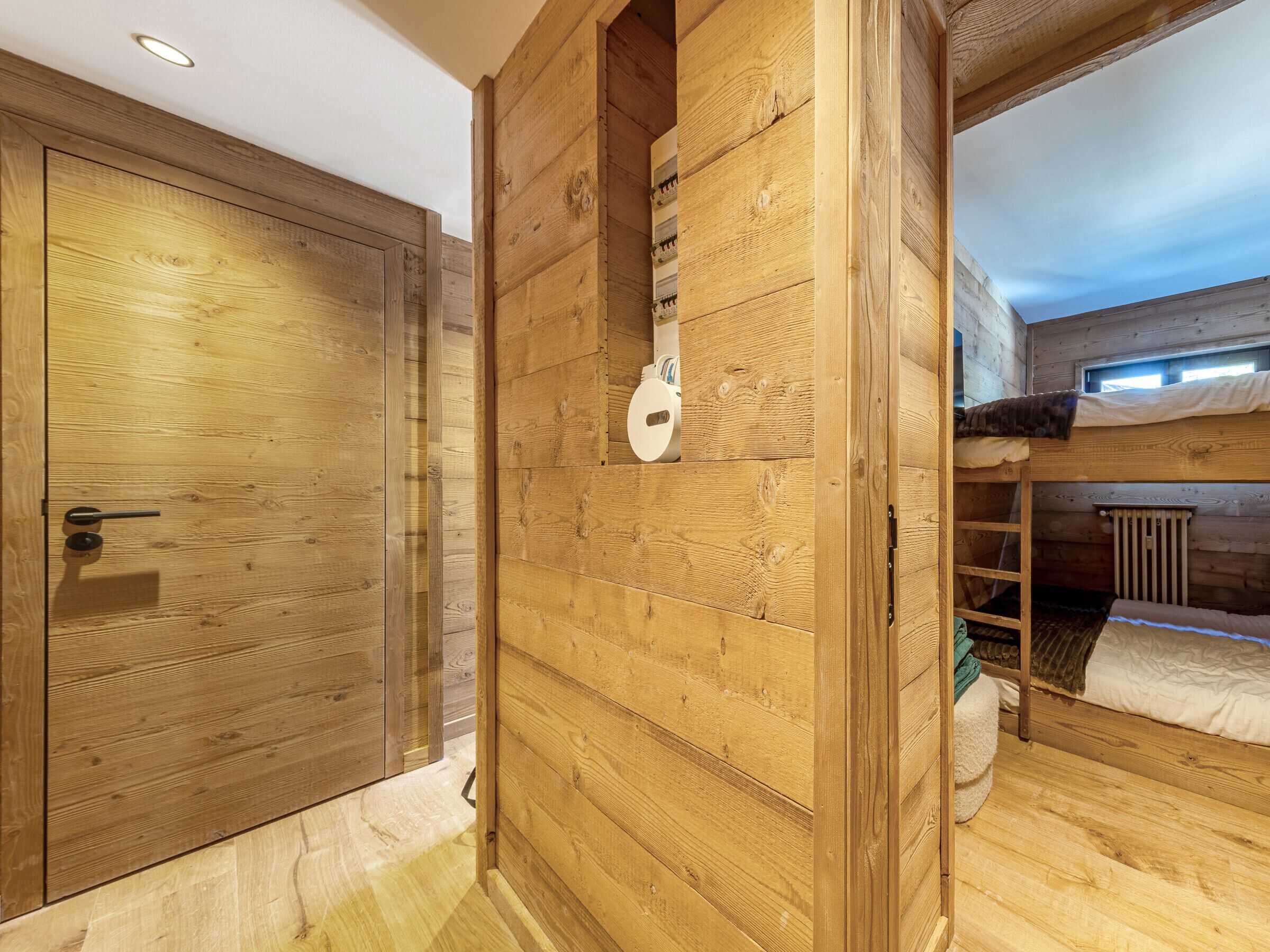 A wooden interior with a bunk bed, a door, and a small window.
