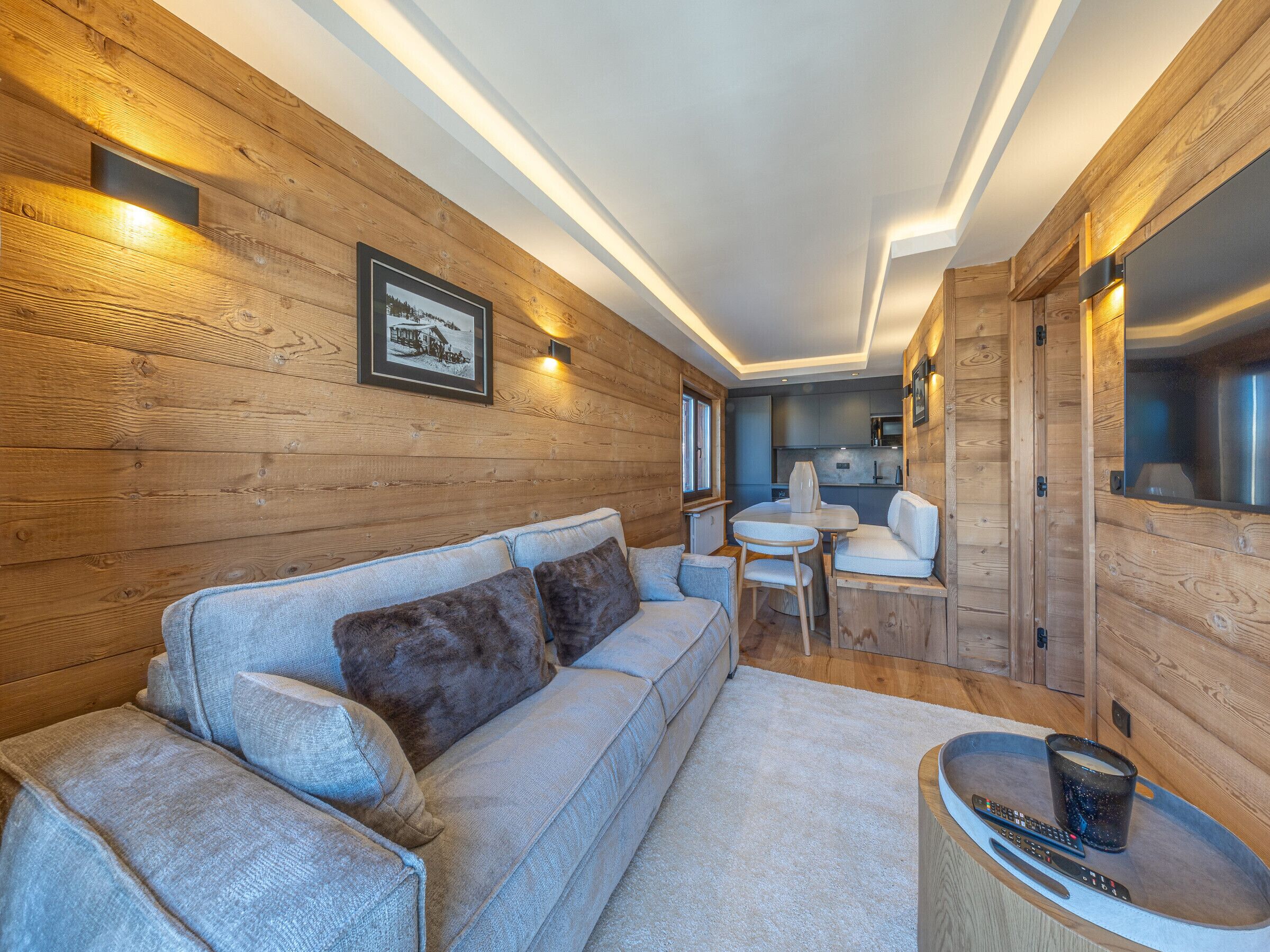 A cozy cabin interior with a sofa, a dining table, and a kitchen area.
