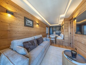 Ein gemütliches Blockhaushaus-Interieur mit einer Couch, einem Esstisch und einer Küchenzeile.