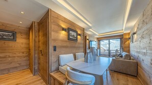 En modern inredning med träpanel, en matplats med bord och stolar, en soffa och en tv som är monterad på väggen.