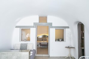 Habitación de hotel con cama, una mesita y un rincón de descanso con cojines.